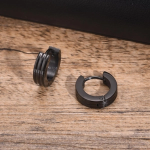 Detail of black stainless steel hoop earrings featuring triple parallel line grooves