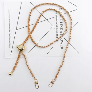 Detail of gold metal phone chain with beige leather weave and quilted ball slider