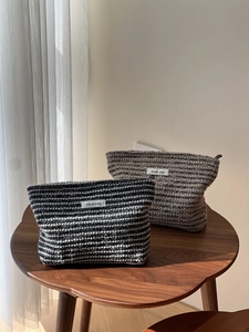 Macro detail of textured tweed fabric cosmetic bags with simple wish label on a wood table