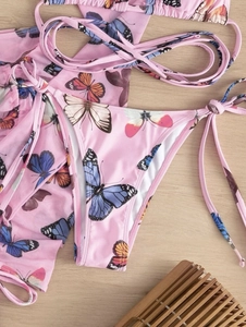 Detail of pink butterfly print bikini and matching sheer mesh sarong on wood background