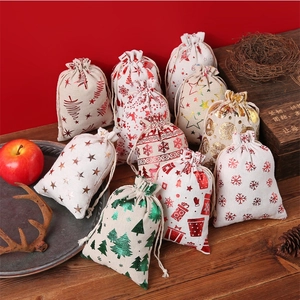 Sacs cadeaux de Noël assortis en coton avec motifs dorés sur une table en bois