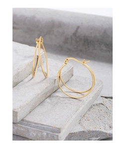 Detailed view of gold double-hoop earrings on a minimalist grey stone background