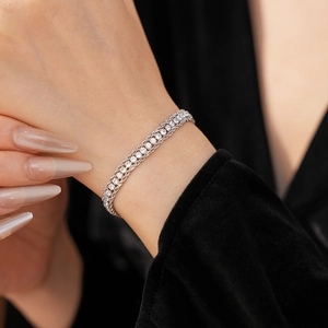 Close-up of sparkling three-row crystal tennis bracelet on model with black velvet outfit