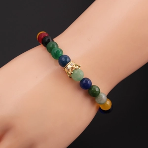 Close-up of multicolor faceted 8mm stone beads bracelet with golden crown charm on wrist