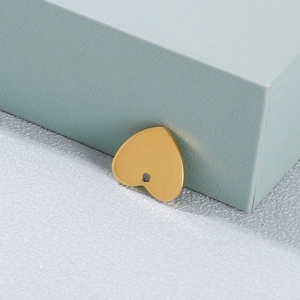 Macro shot of a polished golden heart-shaped stainless steel pendant on a soft textured surface