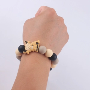 Detail of a silicone beaded bracelet with a cartoon cow charm worn on a wrist