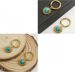 Detailed view of sun-shaped gold earrings with turquoise stone and polished plating