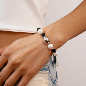 Detail of beaded bracelet with white pearls, black round beads, and silver metal accent