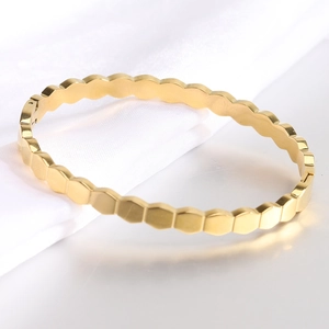 Detailed macro view of the gold hexagonal honeycomb bangle with a side hinge closure