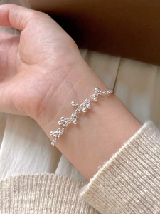 Macro detail of a 925 sterling silver beaded bracelet on a wrist with minimalist design