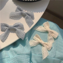 Dettaglio di fermagli a fiocco in tessuto a rete nei colori blu-grigio e bianco crema