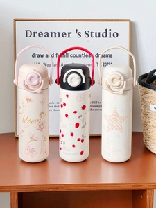 Three cute stainless steel thermal cups with floral and strawberry prints on a wooden table