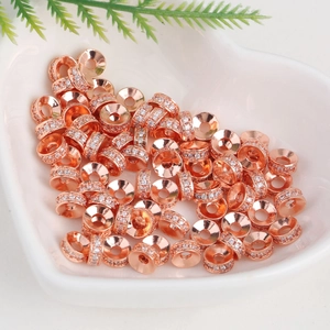 Pile of rose gold zircon wheel spacers in a heart bowl for DIY jewelry making