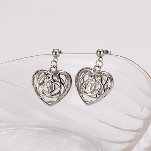 Fashionable stainless steel heart earrings with cutout design on glass stand