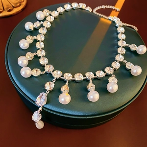 Macro detail of French style waterdrop zircon and pearl necklace with silver chain