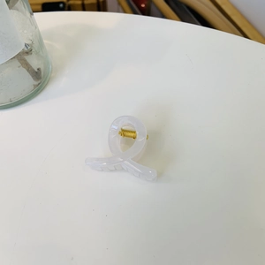 Detail of white translucent hair claw clip with golden metal spring and spiral teeth