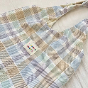 Close-up of purple and blue checkered canvas tote bag with a white fabric brand label