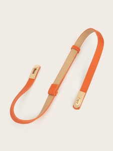 Detail of slim orange leather belt featuring cross grain texture and golden metal lock