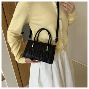Close-up of black pleated PU leather handbag with silver hardware and detachable strap