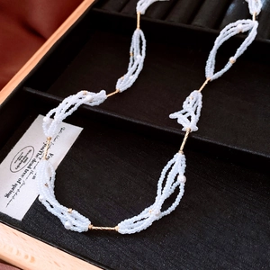 Macro view of multi-strand beaded pearl necklace with golden metal tubes on black velvet