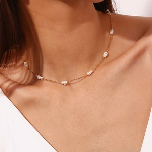 Gros plan d'un élégant collier en perles d'eau douce blanches et chaîne dorée sur un mannequin