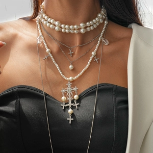 Detail of layered pearl necklaces with crystal-encrusted cross pendants on a model