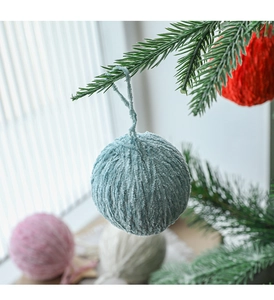 Close-up of assorted wool felt Christmas balls hanging on a tree with soft lighting
