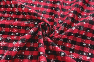 Close-up of red and black buffalo plaid fabric with white snowflake and dot patterns