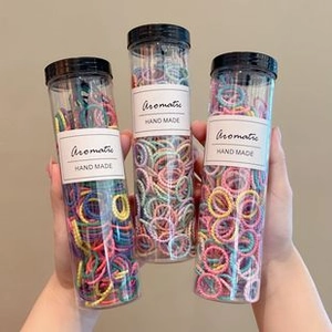 Detailed close-up of three clear jars filled with colorful elastic hair bands for girls