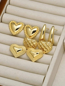 Close-up of heart earrings in gold finish featuring three textured designs in a display box
