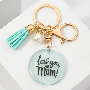Porte-clés avec pompon bleu et pendentif en résine love you Mom avec perle sur fond blanc