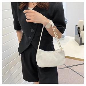 Detail view of a white corduroy shoulder bag with an acrylic chain and gold-tone hardware