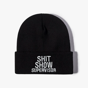 Black knit beanie with white Shit Show Supervisor embroidery on plain background