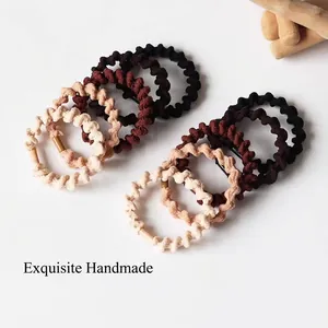 Elastic spiral woven hair ties set in earthy tones displayed on a wooden hand model