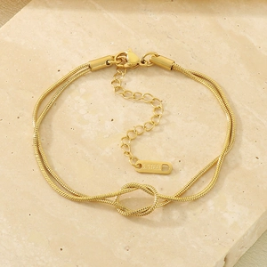 Close-up of a double-strand 18K gold plated snake chain bracelet with a central knot detail