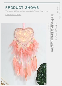 Close-up of pink heart-shaped dreamcatcher with warm LED lights and delicate feathers