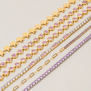 Detailed macro of gold heart-shaped zircon bracelets with pink crystals on white background