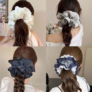 Detail view of four textured fabric scrunchies in lace, floral, and checkered patterns