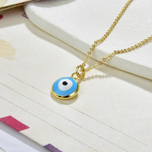 Macro detail of golden Evil Eye pendant with blue enamel on a textured surface