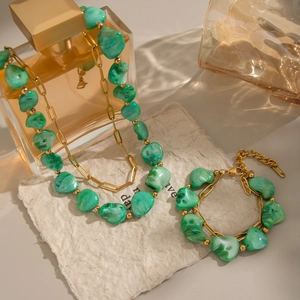 Elegant gold-tone layered necklace and bracelet set featuring irregular green gemstones