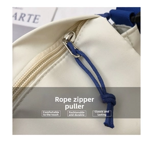 Detail of white canvas messenger bag with blue woven cord zipper pull and durable strap