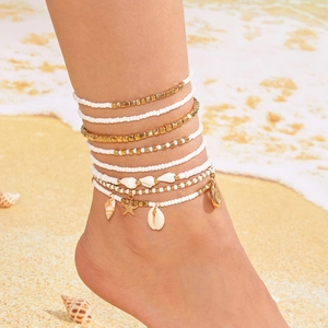 Bohemian gold starfish and seashell layered anklet set worn on a sandy beach