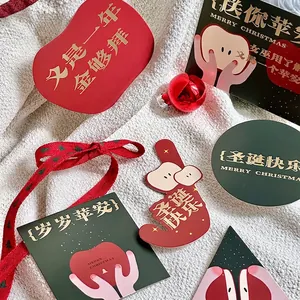 Set di biglietti natalizi con etichette rosse e verdi e stampa in oro su tessuto bianco