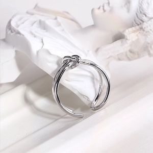 Artistic close-up of a silver knot-designed double ring displayed on a white statue