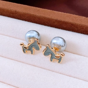 Macro detail of gold horse stud earrings with grey-blue enamel and grey pearls