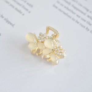Detailed macro view of golden mini hair claw with opal petals and faux pearls