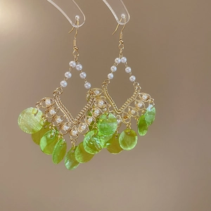 Close-up of pearl beaded tassel earrings with green shell sequins and gold hooks