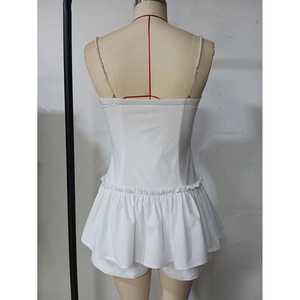 Detail of white backless dress featuring pearl straps and elegant ruffle hemline