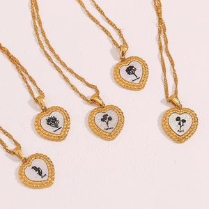 Détail du pendentif fleur de naissance en forme de cœur sur chaîne en acier doré