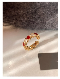 Detail of gold-plated open ring featuring alternating red enamel and clear zircon hearts